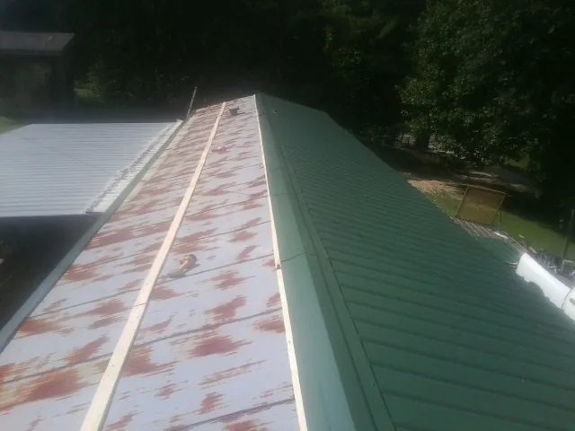 Old rusted panels beside newly installed green metal roofing — Wind Damage Roof Repair by Roofing Brothers in Fort Shaw
