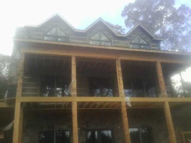 Dormers and porch framing on a large log home under construction — Roof Coating work by our crew in Fort Shaw