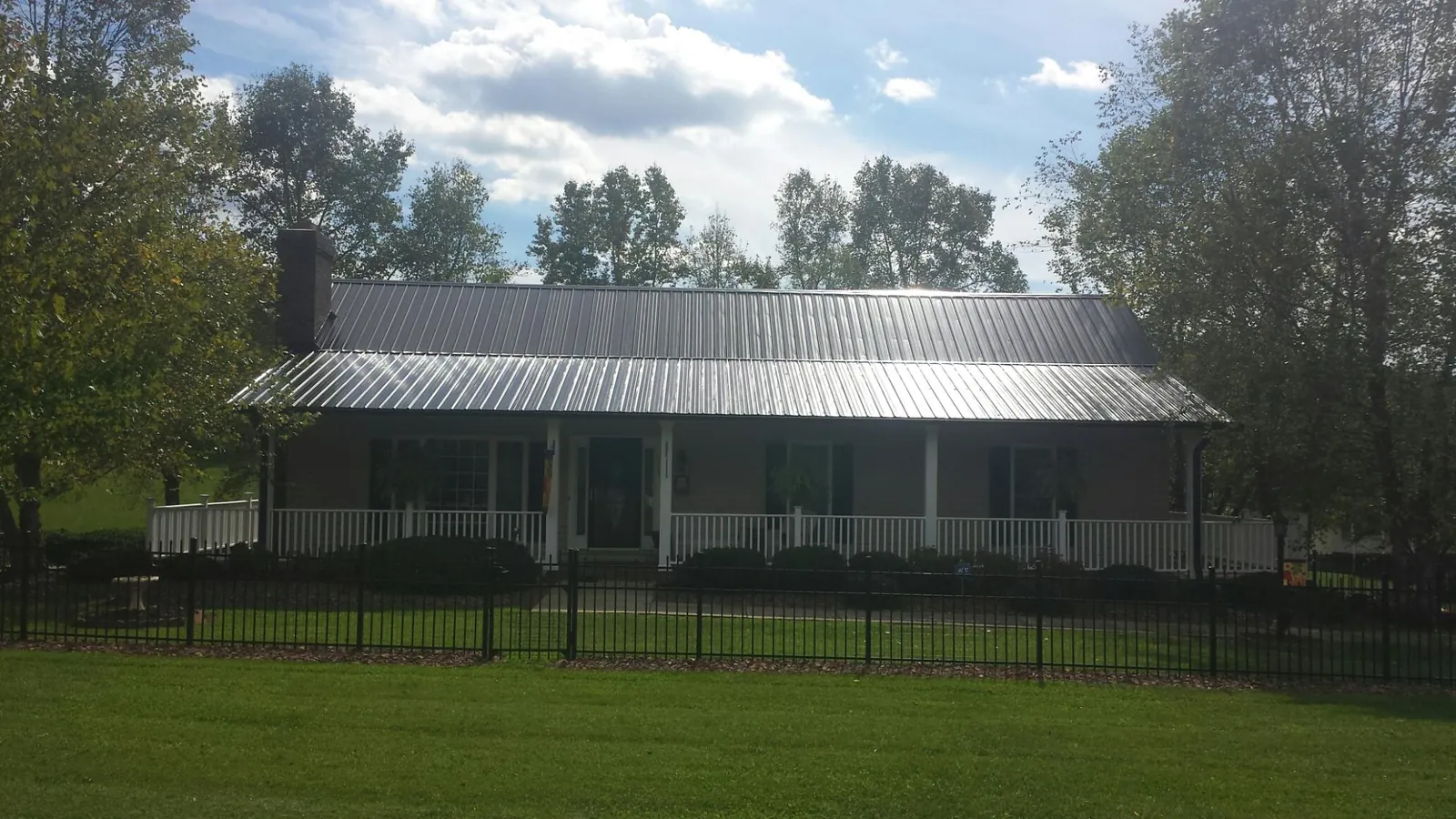 Gray metal roof on a brick ranch with a full width front porch — Gutter Guard Installation work by our crew in Fort Shaw