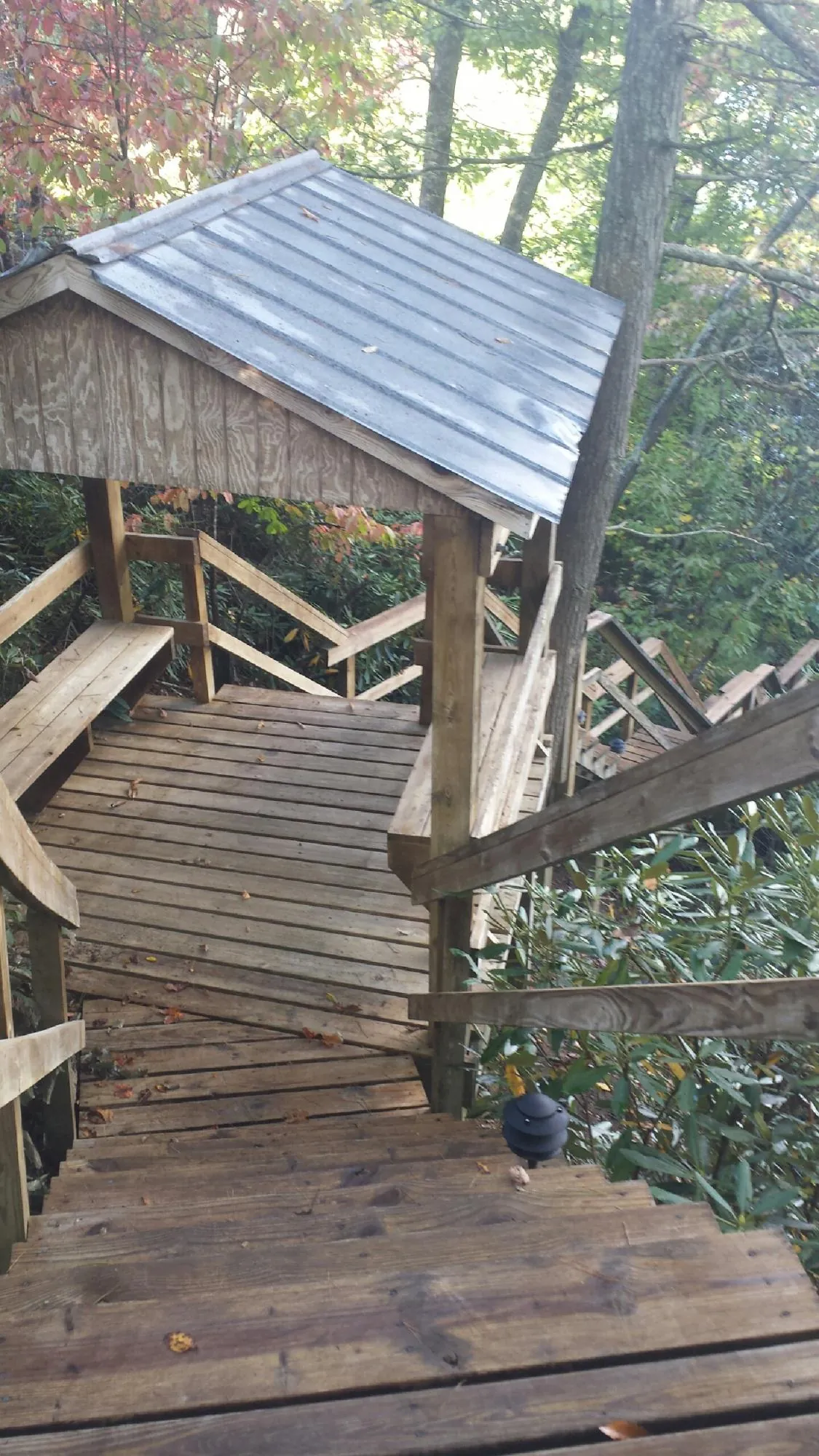 Metal roofed shelter over wooden steps on a wooded walkway — Skylight Repair & Installation work by our crew in Fort Shaw