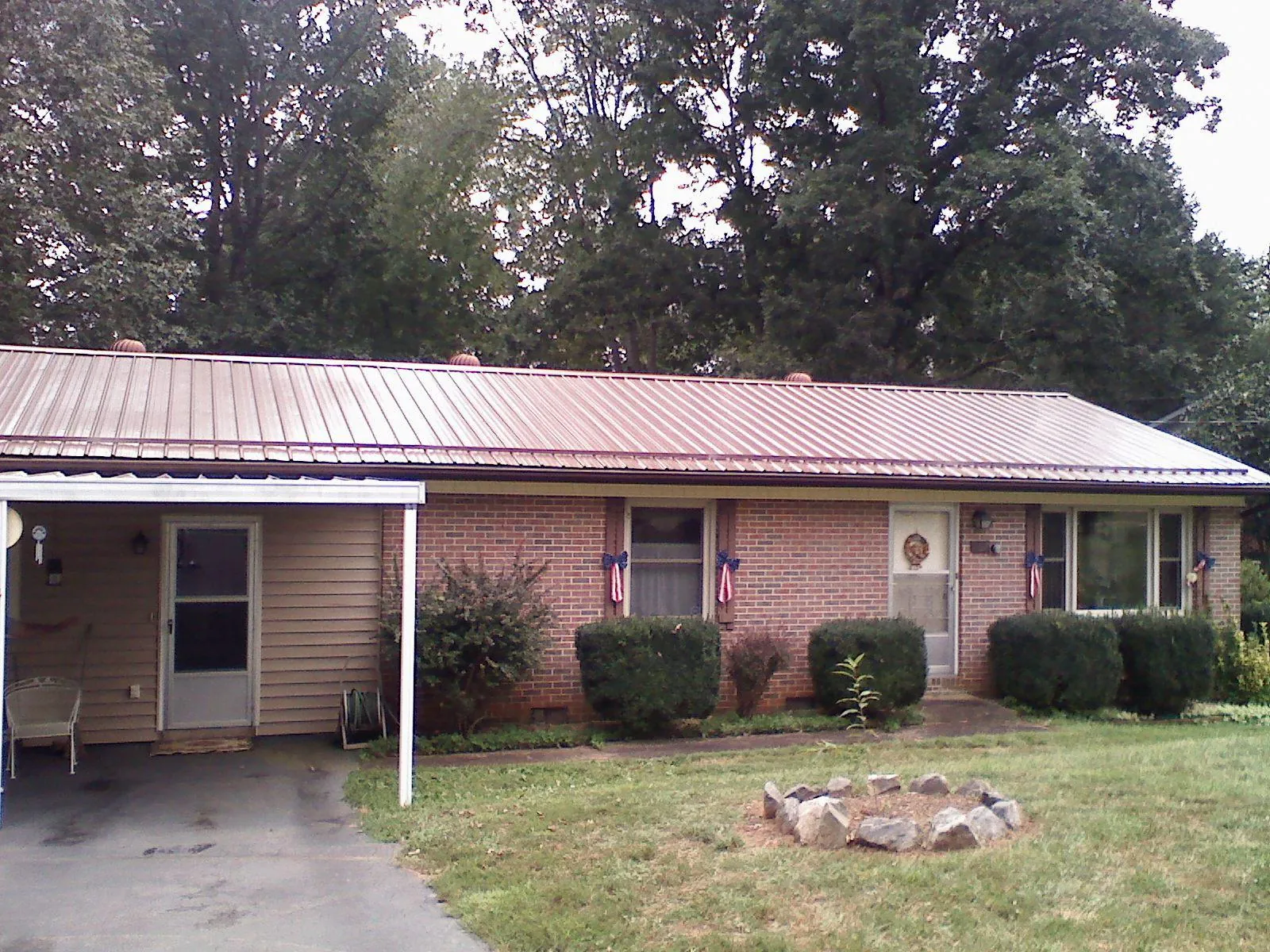 Bronze metal roof and carport on a brick ranch home — Roof Repair work by our crew in Fort Shaw