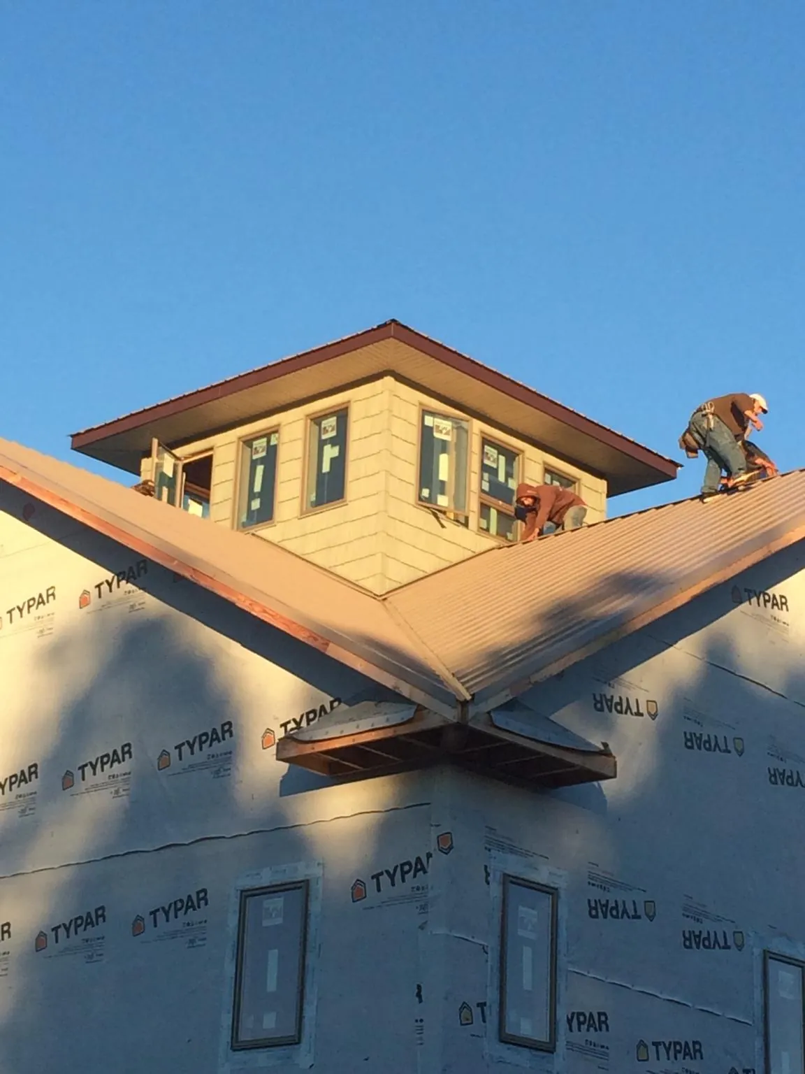 Roofers working around a rooftop cupola on a new metal roof at sunset — Roof Waterproofing in Fort Shaw by Roofing Brothers